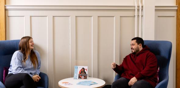 Two people sat speaking to on another.